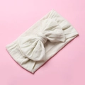 Close-up of cream nylon bow headband showing soft knitted texture on pink backdrop - Grey/White