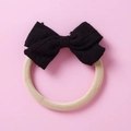 Macro detail of a black knitted bow on a beige high-elasticity nylon baby headband - Black