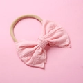 Détail d'un bandeau pour bébé en nylon avec un grand nœud rose sur un ruban élastique - Rose Poudré