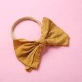 Détail du bandeau bébé en nylon jaune moutarde avec un grand nœud en tricot - Jaune Gingembre