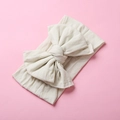 Close-up of cream nylon bow headband showing soft ribbed texture and handcrafted knot - Off White