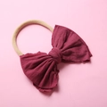 Gros plan détaillé d'un grand nœud en tricot rouge foncé sur un bandeau en nylon souple - Bordeaux