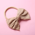 Gros plan du nœud en tricot beige et du bandeau en nylon élastique pour les bébés - Chair