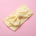 Detail of soft pale yellow nylon baby headband with a large decorative bow - Beige