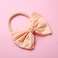 Détail du nœud rose pêche sur un bandeau en nylon souple pour bébés et nourrissons - Pêche