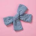 Dettaglio del fermaglio a fiocco blu in pizzo di cotone con ricami floreali su sfondo rosa - Celeste
