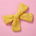 Dettaglio ravvicinato del ricamo in pizzo giallo su un fiocco per fermaglio bimba - Giallo Vivido