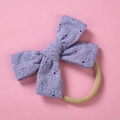 Detailed close-up of lavender cotton bow headband with daisy embroidery and soft nylon band - Purple
