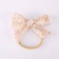 Détail d'un bandeau bébé avec nœud en tulle pêche et broderies florales délicates - Pêche Abricot