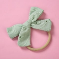 Detail of light green eyelet lace bow on a soft nylon headband for infants - Grass Green