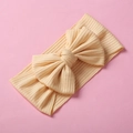 Dettaglio di fascia per neonati in maglia a coste gialla con un grande fiocco decorativo - Beige