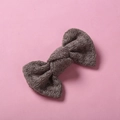 Gros plan d'une barrette nœud en tricot gris foncé avec texture laine sur fond rose - 10*6 cm / Gris foncé