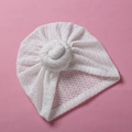Detail der weißen hohlen Strickstruktur und des Donut-Knotens der Baby-Turbanmütze - Weiß