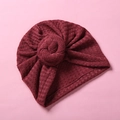 Details der burgunderroten Baby-Turban-Mütze mit Donut-Knoten und Waffelstrick-Textur - Rot