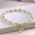Minimalist pearl bracelet with a golden sea turtle pendant on a decorative open book - Turtle & Starfish Detail Style (32352)