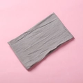 Detail view of a gray soft nylon baby headband with elastic wrinkled texture on pink background - Gray