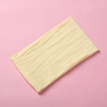 Macro shot of a light yellow nylon baby headband with vertical ribbed texture on pink background - Beige