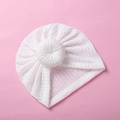 Detailed close-up of white waffle knit baby turban hat with donut knot on pink backdrop - White