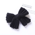 Dettaglio del fermaglio a fiocco in maglia nera con trama di lana su carta bianca - Fermaglio Fiocco in Maglia Nero / Nero