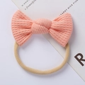 Detailed close-up of pink peach baby headband featuring soft waffle knit bow texture - Pink Orange