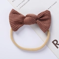 Detail of baby headband featuring brown knit waffle bow and soft beige elastic nylon band - Tan