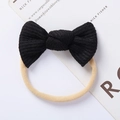 Detail of baby headband with black waffle knit bow and soft nude nylon elastic band - Black