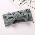 Detail of baby headband with a knit bow in sage green on a minimalist background - Bean Green