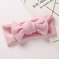 Detail of pink knitted baby headband featuring a large textured bow on a white background - Light Pink