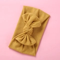 Ginger yellow ribbed knit baby headband with a large elastic bow on pink background - Ginger Yellow