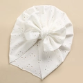 Detailed close-up of white baby turban hat with eyelet embroidery and a layered bow - White