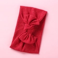 Detalle de la diadema de punto acanalado rojo para bebé con lazo sobre fondo rosa - Rojo