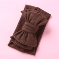 Detail view of dark brown ribbed knit baby headband with oversized bow on pink backdrop - Brown