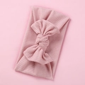 Close-up of soft pink ribbed knit baby headband with a large elastic decorative bow - Dusty Pink