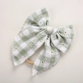 Détail d'un nœud écossais vert avec broderie marguerite sur un bandeau en nylon souple - Plaid Vert Haricot / 11*11 cm