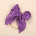 Close-up of a purple linen baby headband featuring a soft bow and elastic nylon band - Purple