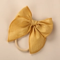Close-up of mustard linen bow headband with elastic nylon band and detailed stitching - Yellow