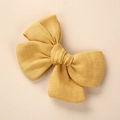 Gros plan détaillé d'une pince à cheveux avec nœud en lin jaune moutarde texturé - 9x8cm / Jaune