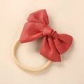 Macro view of brick red linen bow with soft elastic nylon headband for newborns - Orange Red