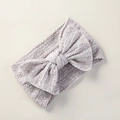 Detail eines weichen Nylon-Baby-Stirnbandes mit Blumenbogen und Zopfstrick-Textur - Hellgrau