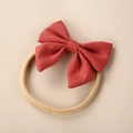 Detail of baby bow headband made of brick red linen fabric with beige nylon strap - Orange Red
