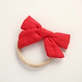 Close-up of red fabric bow headband for babies with hollow jacquard texture and nylon band - Red