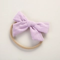 Detailed macro view of light purple knitted cotton bow on soft elastic baby headband - Purple