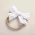 Detailed macro view of white textured cotton bow on soft stretch nylon baby headband - White