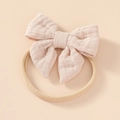 Close-up of soft pink cotton bow and beige elastic nylon headband for infants - Light Khaki