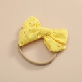 Détail du nœud en dentelle brodée jaune sur un bandeau pour bébé en nylon élastique souple - Jaune vif