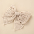 Detail of soft cotton muslin hair bow with white overcast stitching and crinkle texture - 10.5x10.5cm / Nude