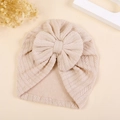 Dettaglio del turbante neonato in maglia beige con motivo a spina di pesce e fiocco - M / Color Tè al Latte