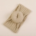 Dettaglio fascia per neonati in maglia beige con motivo a treccia e nodo donut - Confezione OPP individuale / Color Carne (#5)
