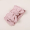 Gros plan d'un bandeau en tricot rose pour bébé avec un nœud et une texture de crochet ajourée - 17x9x5.5cm / Rose Chair