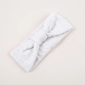Detail van witte gebreide baby haarband met opengewerkte ruitpatronen en een knoopstrik - Koud Wit